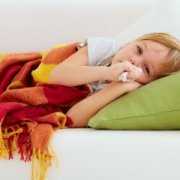 mold-help-tips-for-parents Sick child laying in bed covered with a blanket and holding a tissue